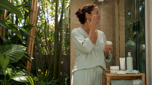 Woman applying moisturizer in sunny bathroom